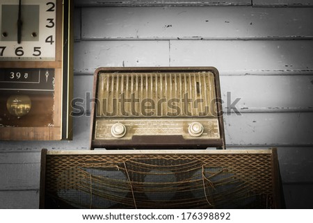 Retro Radio player and clock in room with gray wood wall,
