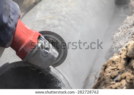 Plumbers cutting concrete water pipes by metal grinding
