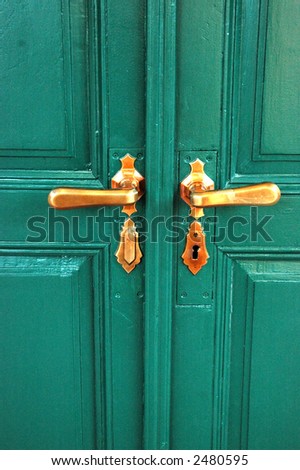 A wooden green door with two knobs