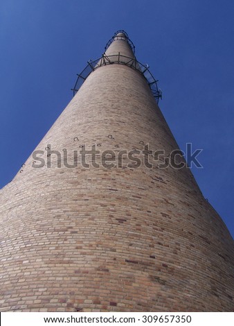 a high chimney against a cloudless blue sky, brick building, view from the worm\'s-eye view/Chimney