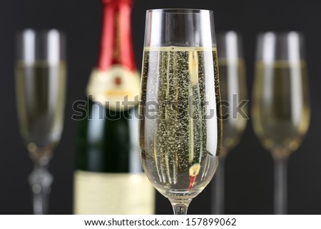 Champagne with bubbles in a glass with a bottle and more glasses in the background