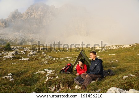 Young people camping in the mountains in fog and enjoying the sunset