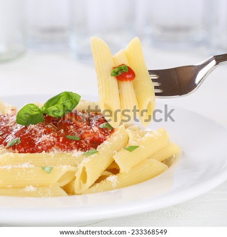Eating pasta Rigate Napoli with tomato sauce with fork on a plate