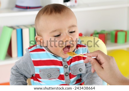 Mother feeding cute child with baby food