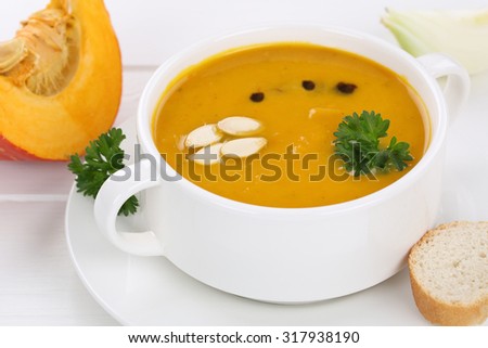 Pumpkin soup with fresh pumpkins in bowl and baguette