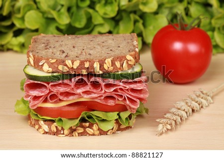 Fresh sandwich with salami, cheese and lettuce on a wooden table