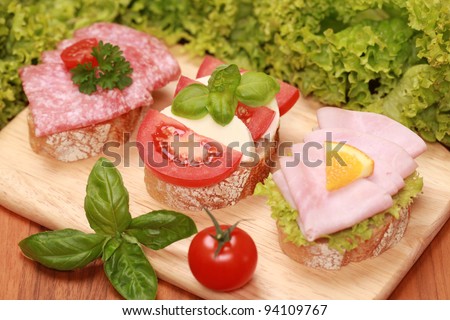 Finger food topped with salami, ham, mozzarella cheese and tomatoes.