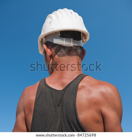 Back of construction worker against blue sky