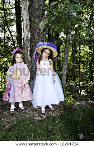 Two little girls dressed up with hats, beads, party dresses and pink sparkle shoes.