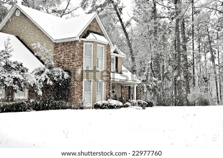 Executive home covered with a white snow blanket on a cold winter day.