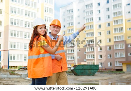 male and female construction workers in a helmet on a background of houses
