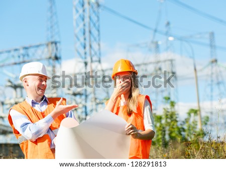 male and female construction workers in the helmet against electrical designs