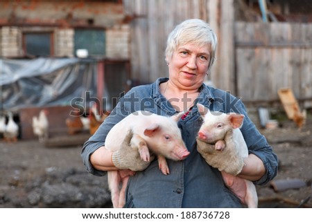 Adult woman keep in the hands of two little pigs. animal husbandry