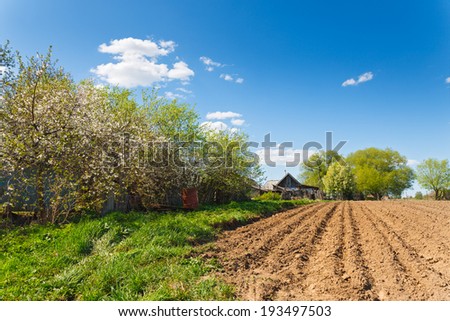 landscape plowed field on a background of rural houses