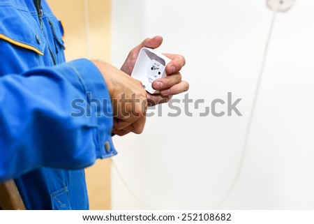 Electrician hands installing electrical wall sockets - closeup, focus on socket