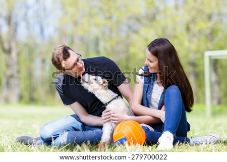 happy young family playing with a dog licking his owner in face as a sign of affection
