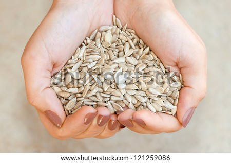Sunflower seeds\' kernel in woman\'s hands forming heart shape