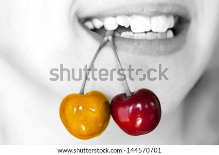 Child holding yellow and red cherries pair with teeth