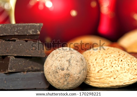 Chocolate slices stack, chocolate ball, almonds on Christmas red balls decoration background