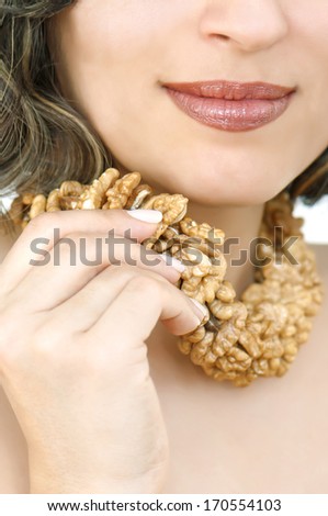 Woman holding necklace from walnut\'s kernel on her neck