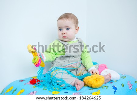 Cute baby. Closeup of a little infant boy in casual clothes playing in nursery with knitting wool and holding a toy
