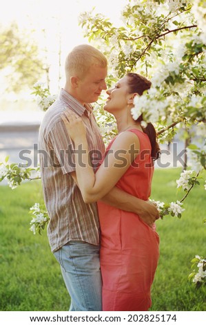 Young beautiful couple in love among apple trees in blossom
