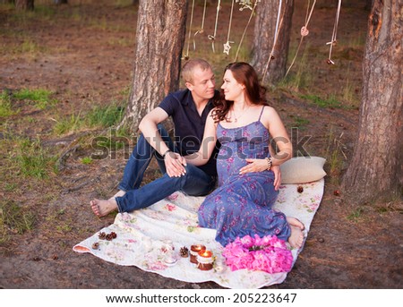 Pregnant couple man husband woman girl wife in love outdoors in the evening hug, rustic style she wears wreath of peony