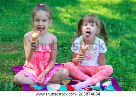 Kids girls friends children eating ice cream and teasing showing off tongues