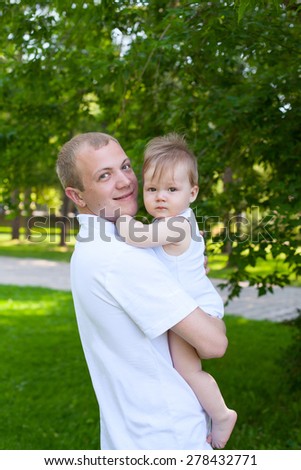 Father dad parent holding baby boy outdoors in summer garden, focus on men\'s face