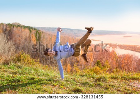 handsome hipster guy standing on his hand on the top of the hill