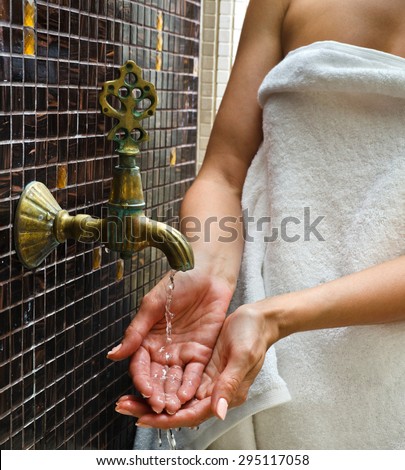 the woman touches water in the Turkish sauna