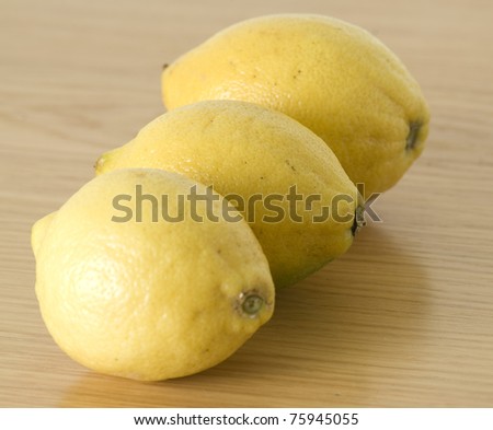 three yellow lemons isolated on a wooden background