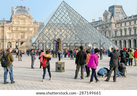 PARIS, FRANCE - MARCH 18, 2015: tourists  in front of the Louvre palace and Louvre pyramid.