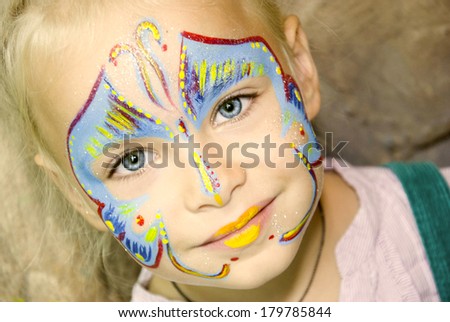 Beautiful girl with blue eyes with painted butterfly on her face