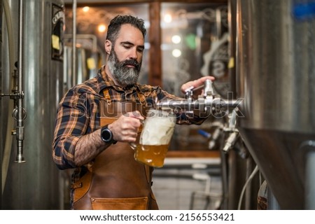 Bearded brewery master tasting beer in production facility. Small family business, production of craft beer. Foto stock © 