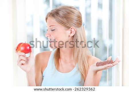 Girl with an apple and candy, fruits or candy dilemma, healthy lifestyle concept