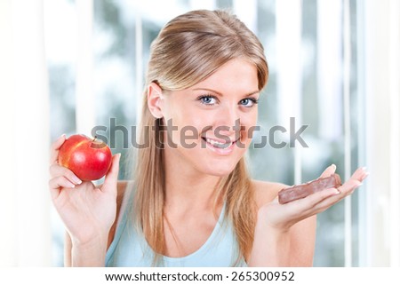 Woman holding apple and candy, fruits or candy dilemma, healthy lifestyle concept