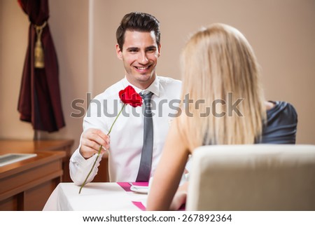 Man is giving rose to his girlfriend at the restaurant
