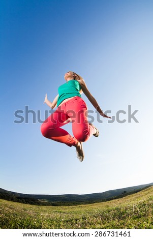 Girl jumping in nature, image shot with fish-eye lens