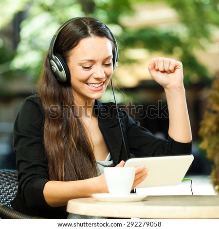 Young woman surfing the net and listening music on digital tablet in a cafe