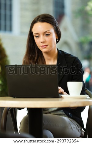 Young woman surfing the net on laptop in a cafe