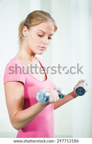 Young woman exercising in gym, using weights