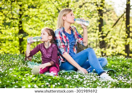 Two sisters drinking water on summer day in park