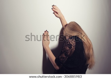 Portrait of woman in despair leaning on wall, intentionally toned.
