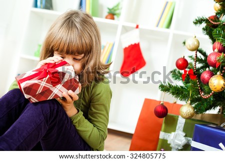 Happy little girl opening her new year\'s presents