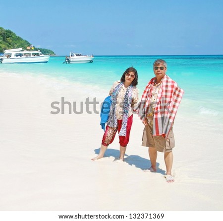 asian elderly man and women travel on clean beach