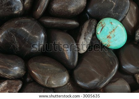 Turquoise stone on top of black river stones