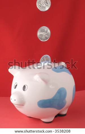 Piggy bank with quarters falling into it with a red background and light shining up from the coin slot