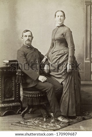 USA - IOWA - CIRCA 1885 - A vintage photo of a young couple. The husband is sitting and the wife is standing. She is dressed in a Victorian style dress. A photo from the Victorian era. CIRCA 1885