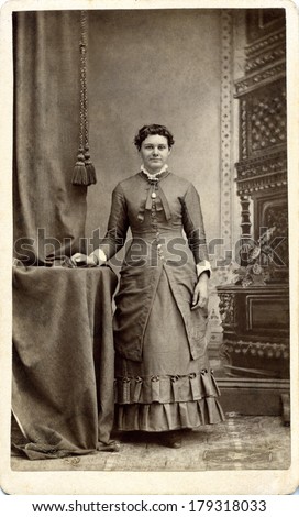 USA - PENNSYLVANIA - CIRCA 1870 A vintage Carte De Visite of a young woman dressed in Victorian style bustle dress standing with her hand placed on a table. Photo is from the Victorian era. CIRCA 1870